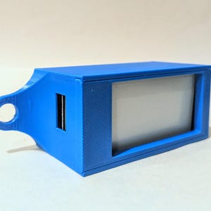 Op de afbeelding: Een blauw rechthoekig elektronisch apparaat met een scherm en een USB-poort. Het apparaat heeft een lus aan één uiteinde en een rechthoekig scherm. Het apparaat is gemaakt van plastic.