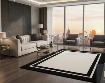 Può includere: Un moderno soggiorno con un grande tappeto rettangolare. Il tappeto ha un centro color crema con un bordo nero. Un divano beige, due poltrone grigie e un tavolino in vetro sono anch'essi presenti. La stanza ha grandi finestre con vista sulla città.