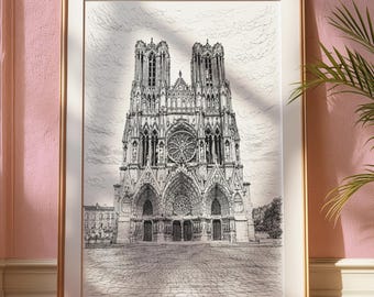 May include: Framed black and white architectural print of a cathedral. The detailed drawing features two tall towers, a rose window, and arched doorways. The print is in a gold frame, displayed against a pink wall with a plant in the corner.