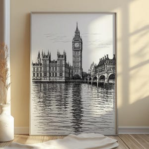 Op de afbeelding: Zwart-wit ingelijste prent van het Palace of Westminster en de Elizabeth Tower, ook bekend als Big Ben, weerspiegeld in het water. Het kunstwerk is een gedetailleerde pen- en inkttekening.