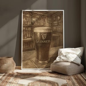 May include: A framed sepia-toned print of a pint of Guinness stout in a pub setting. The glass is filled with dark beer and topped with a creamy head. The Guinness logo is visible on the glass.