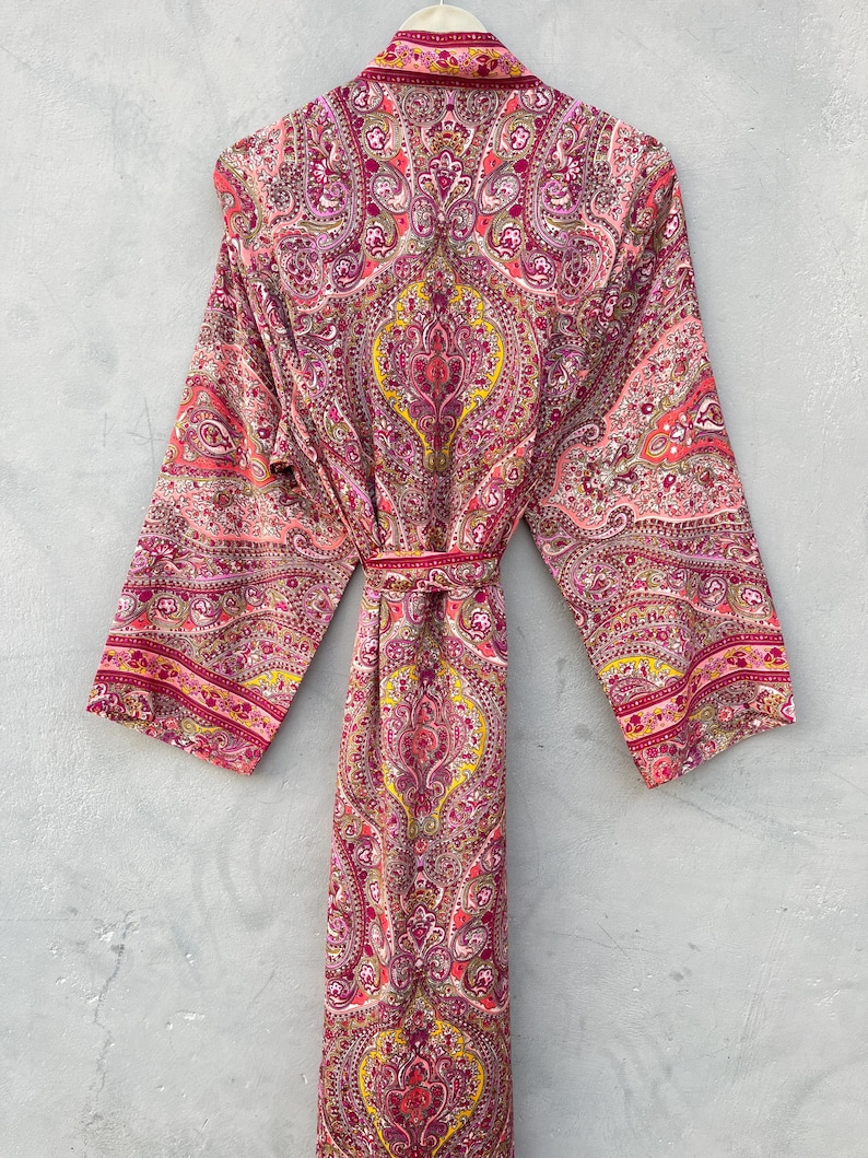 Puede incluir: Bata larga con frente abierto, con un estampado de cachemira en tonos rosa, rojo y amarillo. La bata tiene mangas largas y un cintur&oacute;n a juego. La tela ligera es adecuada para descansar o como prenda de abrigo.