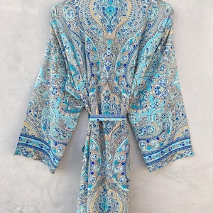 May include: A long, flowing robe with a vibrant paisley pattern in shades of blue, teal, and gold. The robe features wide sleeves and a matching belt. The fabric appears lightweight and suitable for warm weather.