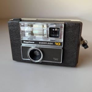 May include: A set of three ceramic mugs with a speckled, matte finish. The mugs are in shades of cream, light brown, and dark brown. Each mug has a simple, minimalist design and a rounded handle.