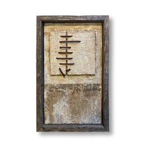 May include: A rectangular wall art piece featuring a textured, off-white canvas panel with a vertical arrangement of dark, rusted metal bars forming a downward-pointing arrow shape, all encased in a weathered, dark gray wooden frame.