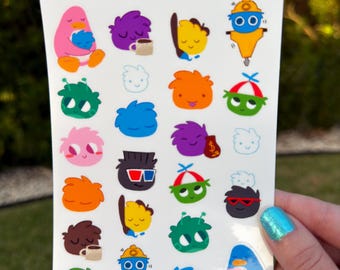 May include: A white sticker sheet titled Puffles Stationery Sticker Sheet @haleyhowe Studio featuring various colourful cartoon creatures. The designs include round characters in pink, purple, orange, blue, green, and brown, some wearing hats, glasses, or holding items like coffee mugs and money bags.