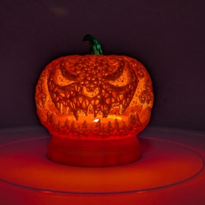 Può includere: Una zucca arancione intagliata con un volto minaccioso, illuminata dall'interno, creando un effetto luminoso. La zucca ha un gambo verde e poggia su una base rotonda. Decorazione di Halloween.