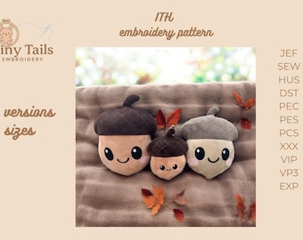 Puede incluir: Tres juguetes de peluche con forma de bellota con caras sonrientes, de varios tamaños, se muestran sobre una superficie marrón. Las bellotas tienen gorros marrones y grises, con cuerpos de color canela. La imagen incluye el texto "Tiny Tails Embroidery" y "ITH embroidery pattern".