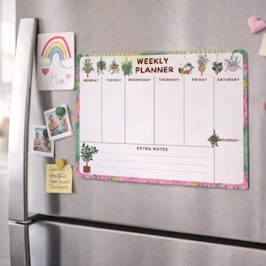 May include: A magnetic weekly planner with a floral border and plant illustrations. The planner is attached to a stainless steel refrigerator door, along with a drawing of a rainbow, photos, and sticky notes.