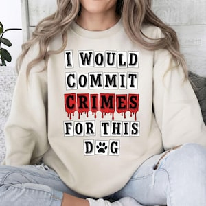 May include: A beige sweatshirt with the text "I WOULD COMMIT CRIMES FOR THIS DOG" in a bold, black font. The word "CRIMES" is in red with a dripping blood effect. The design includes a paw print.