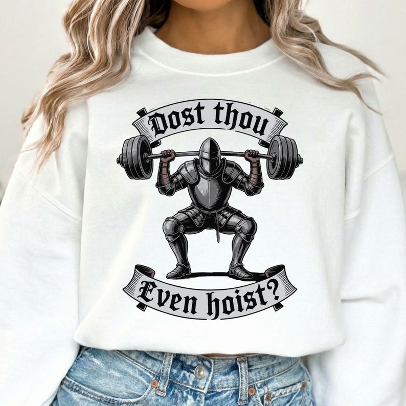 May include: White sweatshirt featuring a graphic of a knight in full armor lifting a barbell. The text "Dost thou" is above the knight, and "Even hoist?" is below. The knight is in a squat position, with the barbell overhead.
