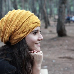 Pode incluir: Gorrinho de malha amarelo mostarda com design de tran&ccedil;a. O chap&eacute;u &eacute; feito de um fio macio e texturizado e tem uma bainha canelada. Um acess&oacute;rio quente e elegante para o clima frio.