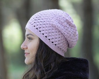 May include: A light purple crocheted beanie hat with a slouchy fit. The hat is made with a delicate stitch pattern and has a soft, cozy feel.