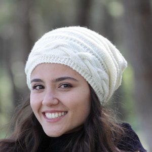 Pode incluir: Um gorro de malha creme com um design de malha entran&ccedil;ada. O chap&eacute;u &eacute; feito de um fio macio e texturizado e tem um ajuste confort&aacute;vel e folgado. Este chap&eacute;u de inverno &eacute; perfeito para se manter aquecido em climas frios.