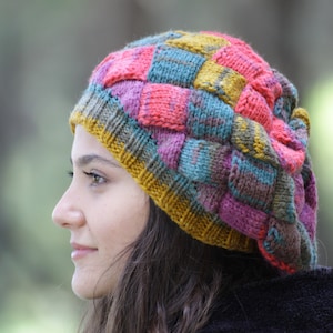 May include: A colourful knitted beanie with a patchwork design in shades of pink, blue, green, and yellow.