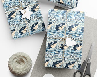 May include: Several wrapped gifts with shark-themed wrapping paper. The paper features a repeating pattern of blue sharks swimming in blue and white waves. Each gift is tied with twine and a white tag. A ball of twine and scissors are also present.
