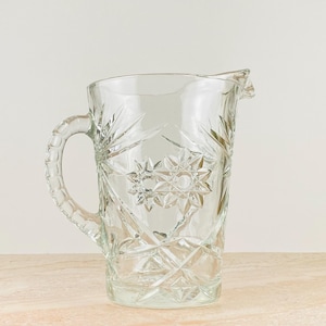 May include: A white ceramic mug with a black handle and the text "But First, Coffee" in a handwritten style. The mug is on a white surface. The mug is approximately 4 inches tall.