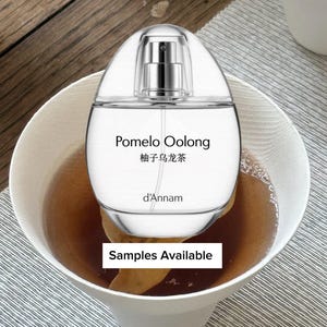 May include: A clear perfume bottle with a silver atomizer, labeled "Pomelo Oolong" in English and Chinese. The bottle is inside a white bowl filled with a brown liquid. The text "Samples Available" is displayed on a white rectangle.