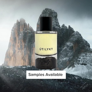 May include: A rectangular perfume bottle with a black cap and a clear glass body. The bottle contains a light yellow liquid and has the word "ÚTILYKT" printed on the front. The image also includes the text "Samples Available".