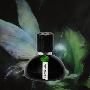 May include: A black perfume bottle with a wooden cap, labeled "GreenFairy." The bottle has a round base and a short neck. The background features a green and blue fairy wing design.