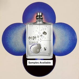 May include: A clear rectangular perfume bottle with a silver cap, labeled "Molecule 01 Escentric Molecules." The bottle is centered against a backdrop of four blue orbs and a beige background. The text "Samples Available" is at the bottom.