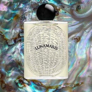 May include: A rectangular perfume bottle with the word "LUNAMARIS" in a decorative oval design. The bottle has a black spherical cap and is set against a shimmering, iridescent background.