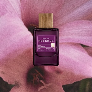 May include: A rectangular glass perfume bottle with a dark purple tint and a light brown wooden cap. The label reads CLEAN RESERVE, SCENT skin [intense], TYPE Intense parfum, and ESSENCE sexy & seductive, featuring a small white flower graphic.