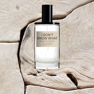May include: A clear glass perfume bottle with a black cylindrical cap. The label features the text I DON'T KNOW WHAT, fragrance enhancer, D.S. & DURGA, and eau de parfum 100 ml. The bottle has a cylindrical shape and contains a clear liquid.