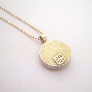 May include: Silver necklace with a round pendant. The pendant has a textured surface and the inscription "925 MW" on the back.