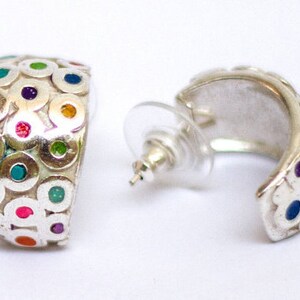 May include: Silver hoop earrings with a colorful circle pattern. The circles are filled with different colors, including pink, blue, green, and yellow.