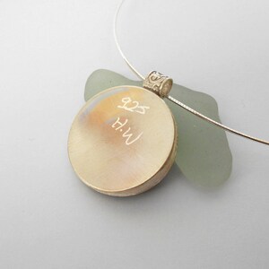 May include: A silver pendant necklace with a round, engraved disc. The disc has the inscription "H.W. 8.25" on it.