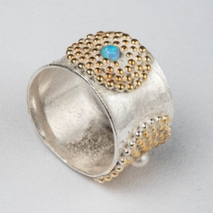 Könnte beinhalten: Ein silberner Ring mit einem gold- und silberfarbenen, strukturierten Band und einem blauen Opal-Edelstein.