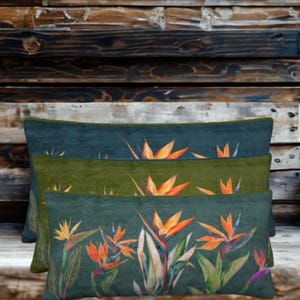 May include: Three rectangular throw cushions stacked vertically, each featuring a botanical print of orange and yellow bird of paradise flowers. The top cushion is dark teal, the middle is olive green, and the bottom is a deep forest green.