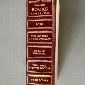 Op de afbeelding: Een vintage Reader's Digest Condensed Books-volume. De rug is diep bordeauxrood met gouden letters en decoratieve accenten. Titels zijn onder meer "Lobo", "The Century of the Surgeon" en "Warm Bodies". Volume 4, 1957.