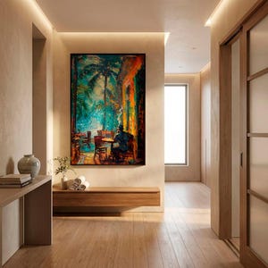 Puede incluir: Pintura al &oacute;leo de una escena de caf&eacute; con una persona sentada a una mesa, palmeras y colores vibrantes. La obra de arte enmarcada cuelga de una pared beige. La habitaci&oacute;n tiene un banco de madera, un jarr&oacute;n y una planta.
