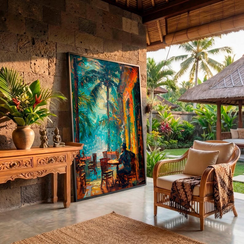 Puede incluir: Una escena al aire libre presenta una gran pintura enmarcada que representa una escena de caf&eacute; con palmeras. Una consola de madera tallada con un jarr&oacute;n de flores y peque&ntilde;as estatuas. Una silla de mimbre con cojines y una manta estampada est&aacute; cerca.