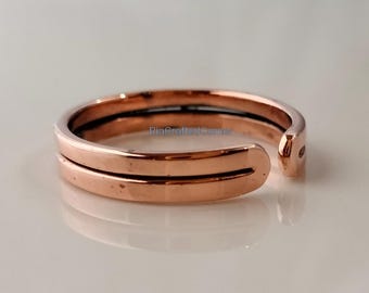 Op de afbeelding: Een verstelbare ring van roségoud met een dubbelbandontwerp. De ring heeft een gladde, gepolijste afwerking en een kleine opening aan één kant voor verstelbaarheid. De ring is ontworpen om op een vinger of teen te worden gedragen.
