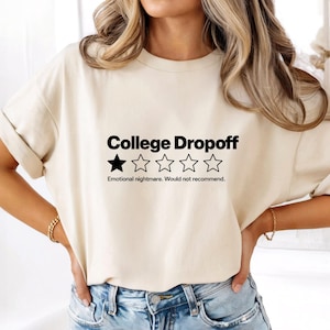 May include: A cream-colored short-sleeve t-shirt featuring the black text College Dropoff above a single filled-in star and four empty star outlines, with the text Emotional nightmare. Would not recommend. printed in black below the stars.