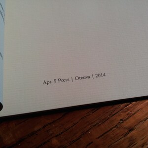 May include: Close-up of the back cover of a book with the text "Apt. 9 Press | Ottawa | 2014" printed in black on a cream-colored background.