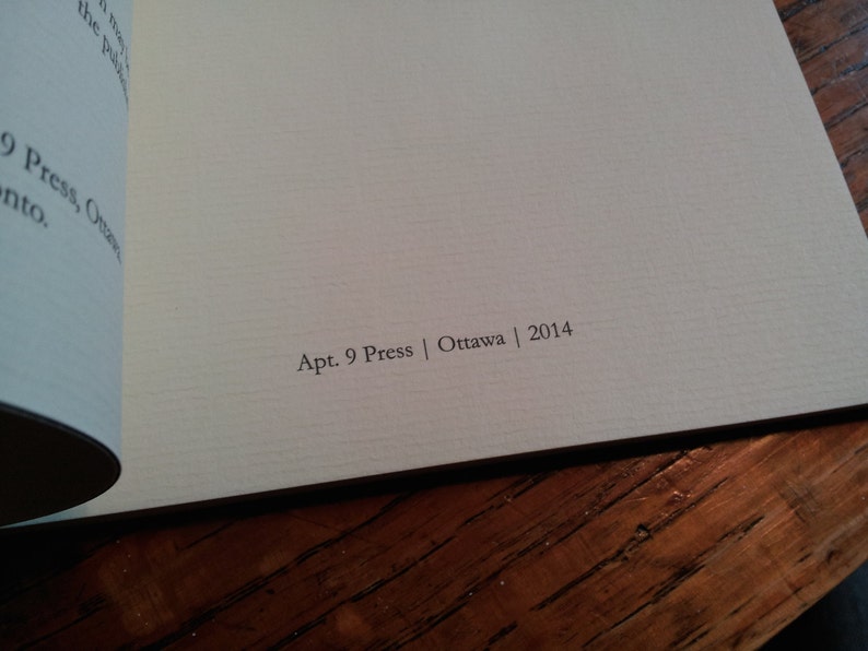 May include: Close-up of the back cover of a book with the text "Apt. 9 Press | Ottawa | 2014" printed in black on a cream-colored background.