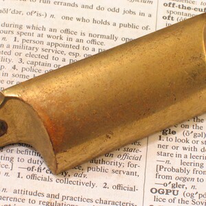 May include: A brass cabinet door pull with two holes for mounting. The pull is curved and has a smooth, polished finish.