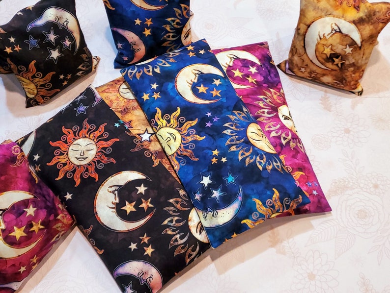 May include: Five decorative pillows with a sun and moon design. The pillows are made of a soft, textured fabric and feature a variety of colors, including blue, purple, gold, and black. The pillows are perfect for adding a touch of whimsy to any room.