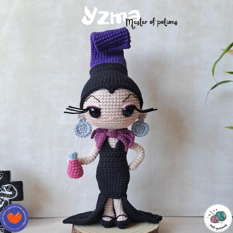 K&ouml;nnte beinhalten: Geh&auml;kelte Puppe einer Figur in einem schwarzen Kleid, einem lila Schal und einem lila Hut. Die Puppe hat gro&szlig;e Augen, lange Wimpern und baumelnde Ohrringe. Die Puppe h&auml;lt eine rosa Zaubertrankflasche. Der Text "Yzma Master of potions" steht &uuml;ber der Puppe.
