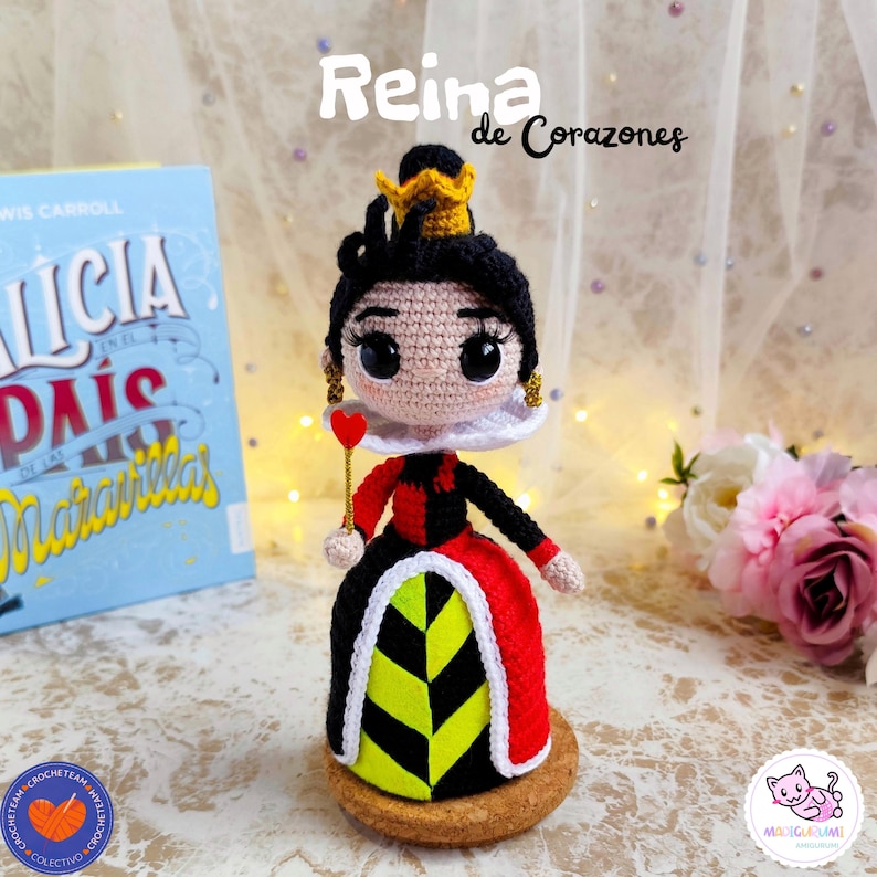 K&ouml;nnte beinhalten: Handgefertigte H&auml;kelpuppe der Herzk&ouml;nigin aus Alice im Wunderland. Die Puppe hat ein schwarz-rotes Kleid, eine goldene Krone und h&auml;lt ein herzf&ouml;rmiges Zepter. Der Text "Reina de Corazones" ist &uuml;ber der Puppe zu sehen.