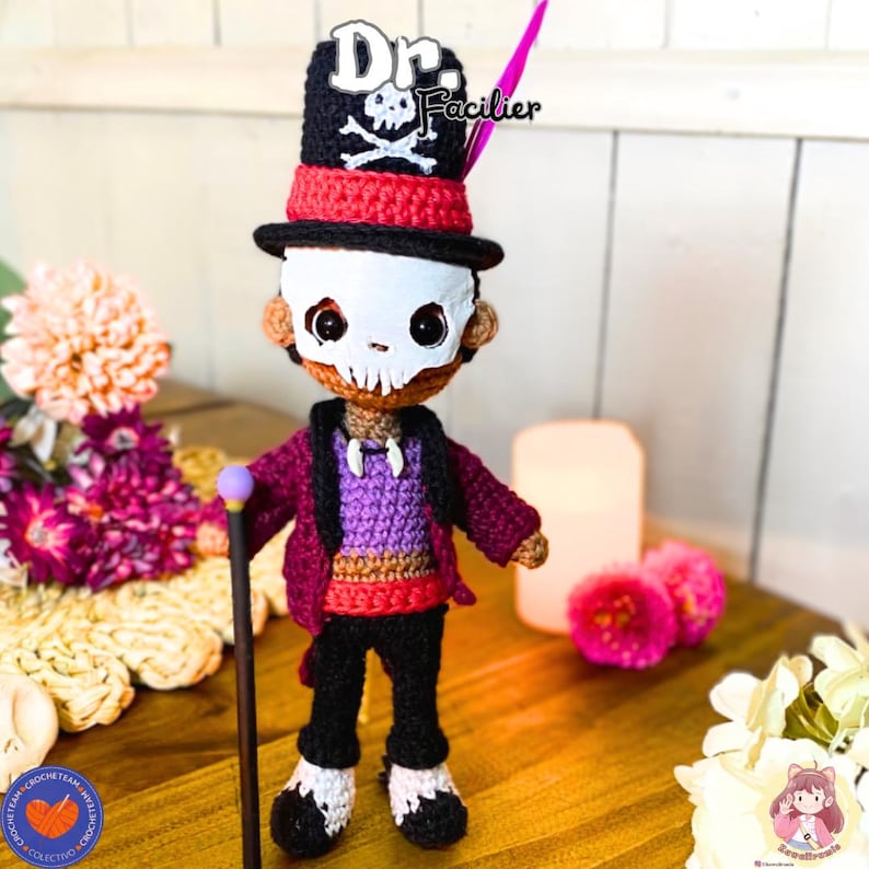K&ouml;nnte beinhalten: Geh&auml;kelte Puppe von Dr. Facilier, mit einem schwarzen Zylinder mit Totenkopf und gekreuzten Knochen, einer wei&szlig;en Totenkopfmaske und einer lila Jacke. Die Puppe hat einen Stock mit lila Spitze.