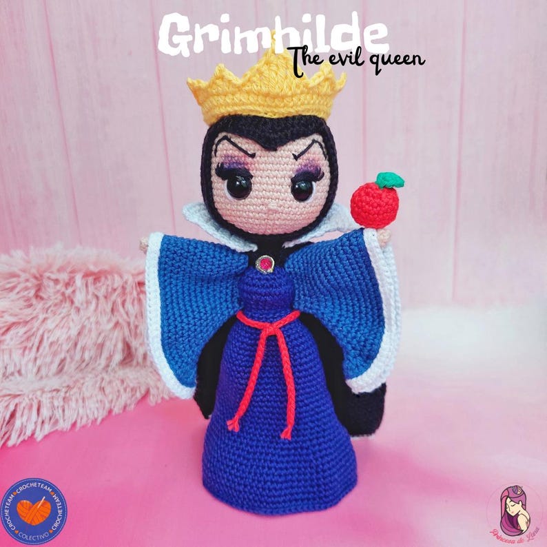 K&ouml;nnte beinhalten: Geh&auml;kelte Puppe von Grimhilde, der b&ouml;sen K&ouml;nigin, in einem blauen Kleid mit roter Schleife und goldener Krone. Die Puppe h&auml;lt einen roten Apfel. Der Text "Grimhilde the evil queen" steht dar&uuml;ber.