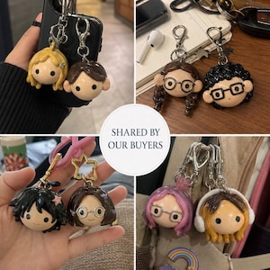May include: A collection of custom character keychains featuring sculpted heads with various hair colors, styles, and accessories like glasses and headphones. Each keychain includes a silver-toned metal lobster clasp for attachment to bags or keys.