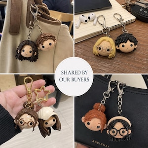 May include: A collection of character keychains featuring stylized heads with various hair colors, styles, and accessories like glasses or hats. Each keychain includes a metal chain and a lobster clasp, showcasing diverse facial expressions and designs.