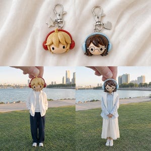 May include: Two keychains featuring miniature figures with headphones. One figure has blonde hair and red headphones with a star charm. The other has brown hair, round glasses, and light blue headphones with a heart charm. Both have metal clasps.