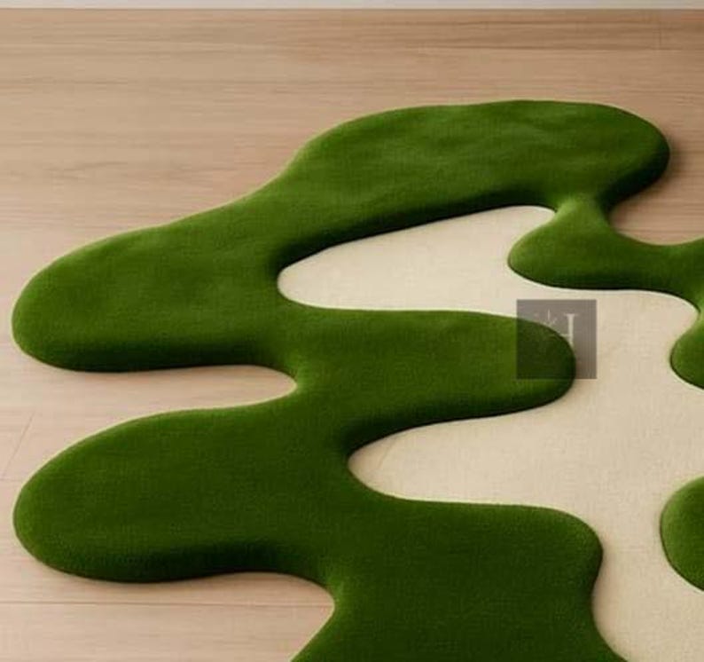 May include: A green and cream-colored rug with an organic, flowing design. The rug features a vibrant green, plush texture that contrasts with the cream-colored sections. The unique shape adds a modern touch to any room.